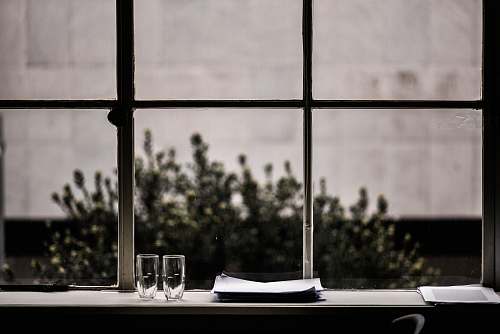 home decor grayscale photography of two clear drinking glasses and plates near window table
